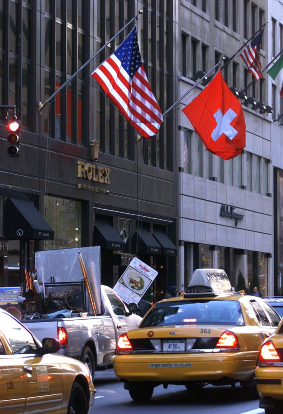 Amerikanische und Schweizer Flagge an der Fassade eines hohen Gebäudes.